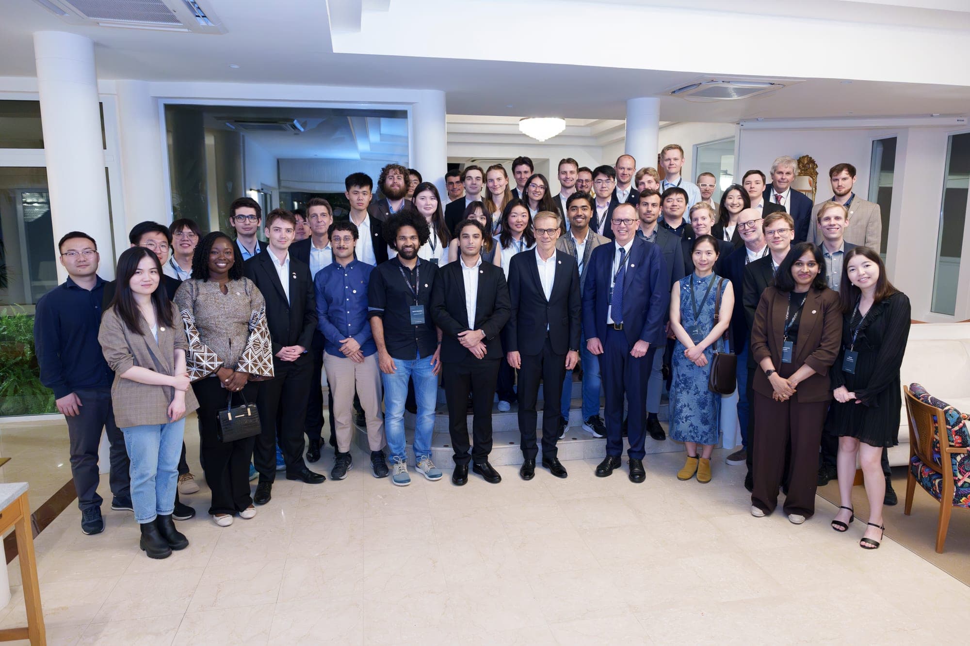 A large group photo of WASP PhD students and hosts in a bright reception room