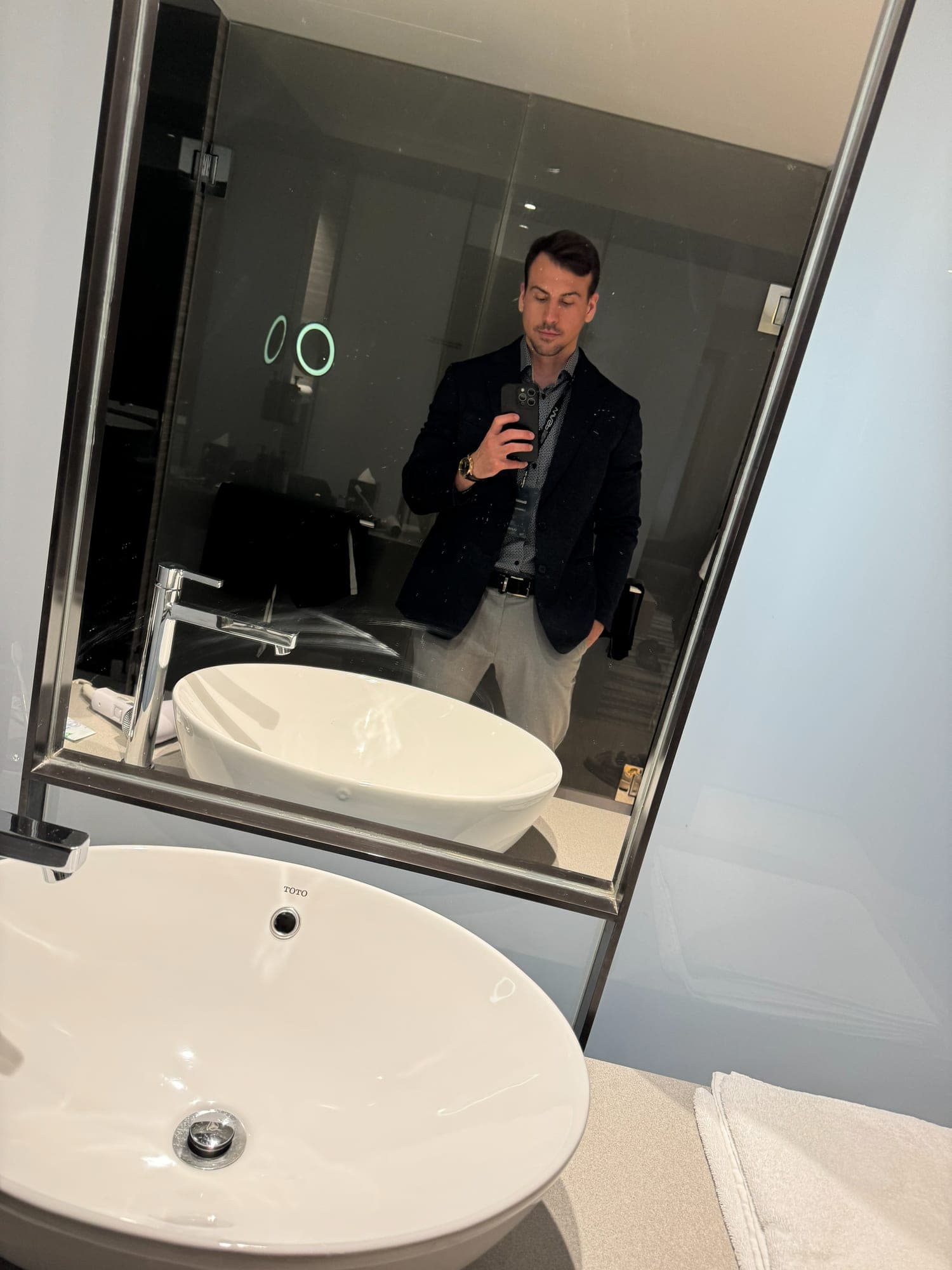 Dominik taking a mirror selfie in a blazer and lanyard