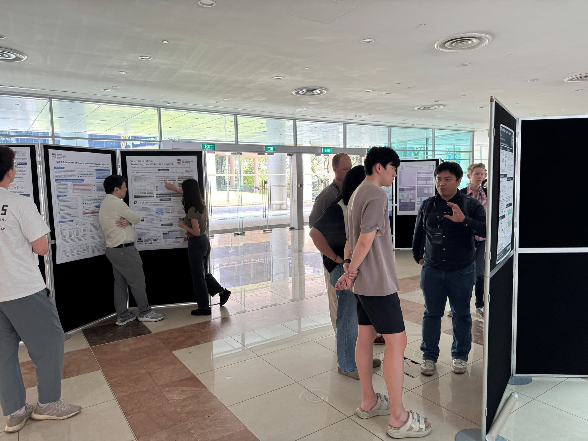 Students and researchers discussing research posters on boards in a bright glass-walled hall