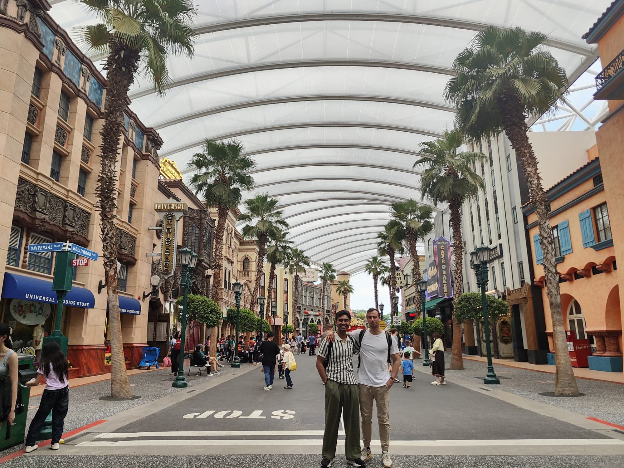 Two WASP students posing on a palm-lined street under a white canopy at Universal Studios Singapore
